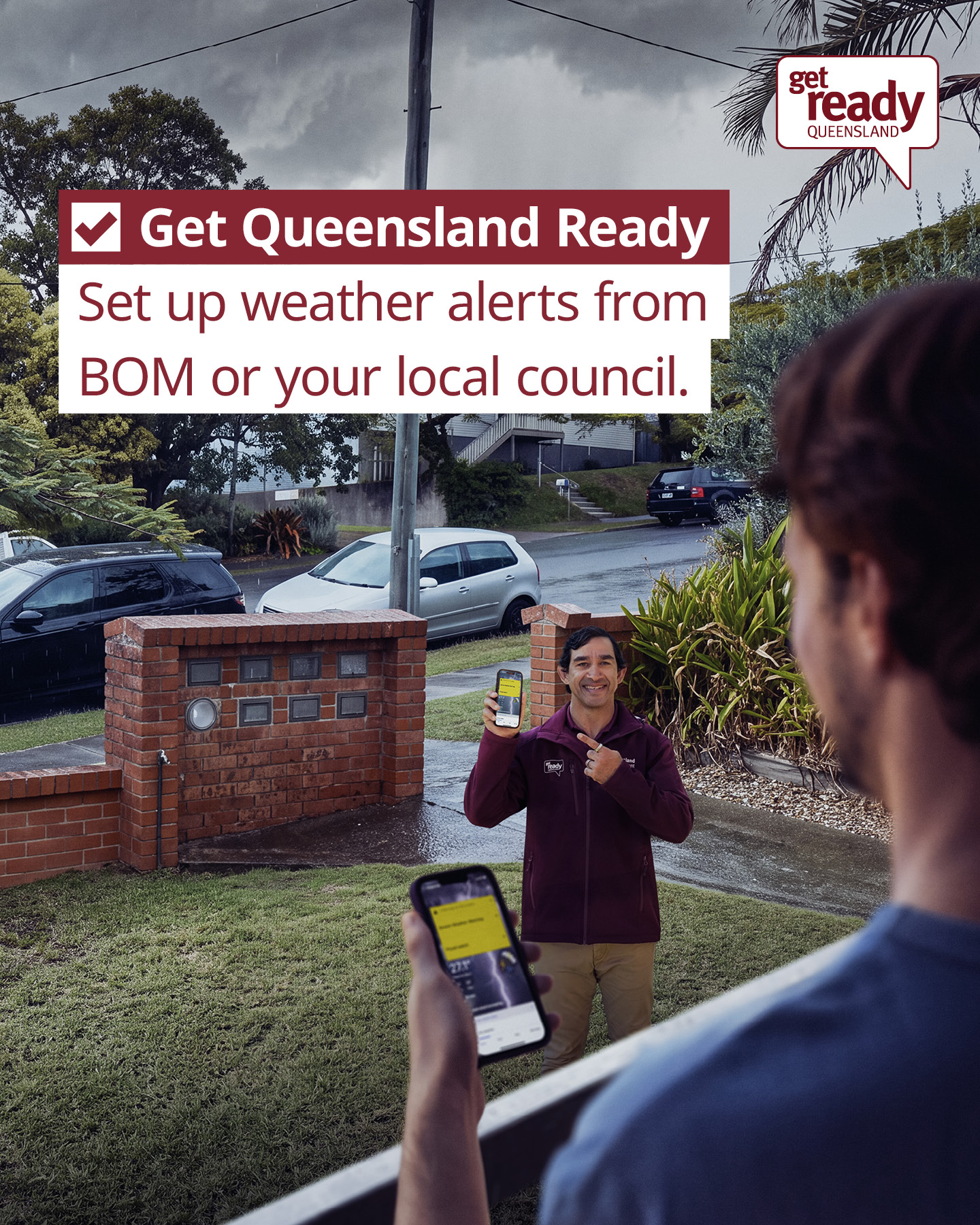 The back of a man holding a phone looking at another man smiling showing his phone with the BOM weather app on it 