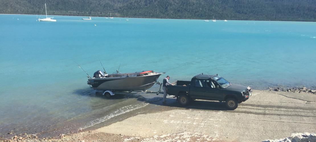 Man hitching boat to ute at boat ramp