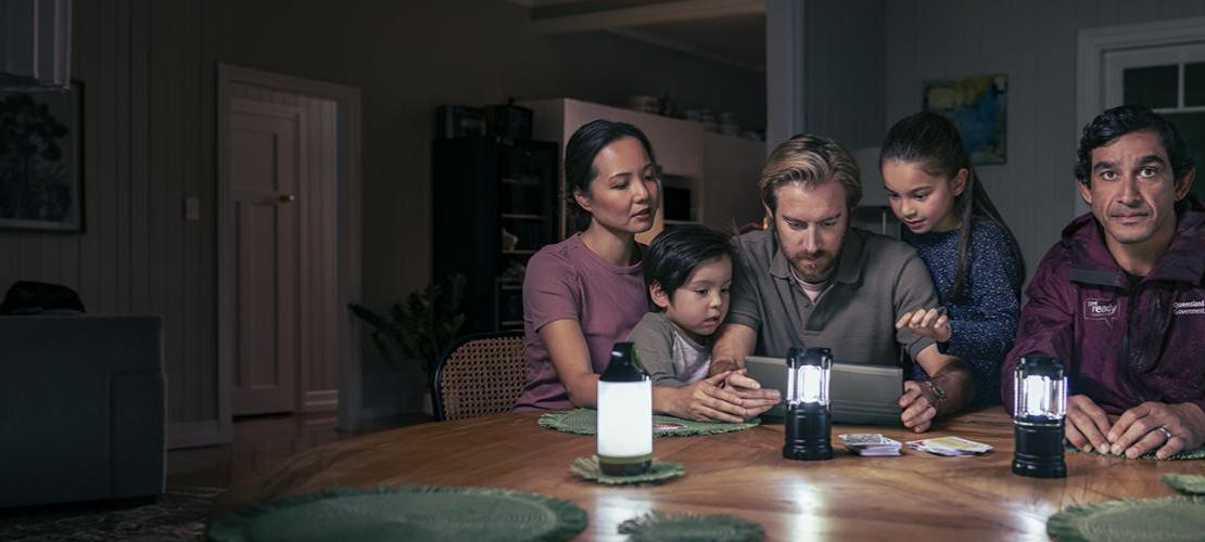 Johnathan Thurston sitting with a family in a house with no power. The family is creating a plan on a tablet.