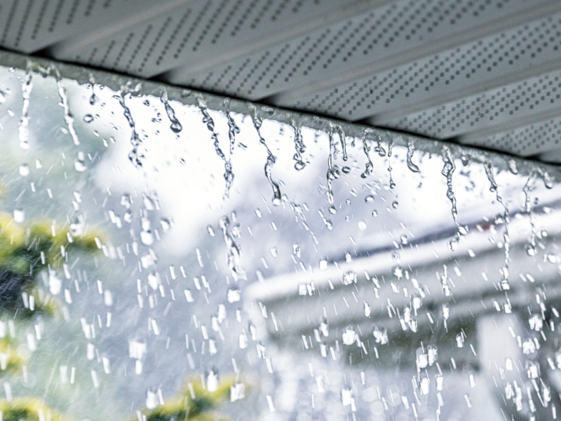 Heavy rain falling pouring off of a tin roof