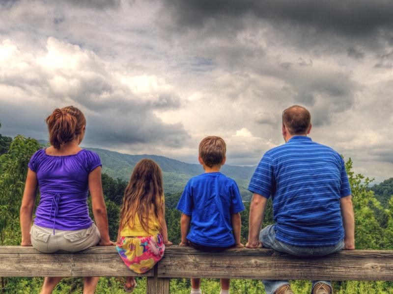 Family sitting on fence looking at storm