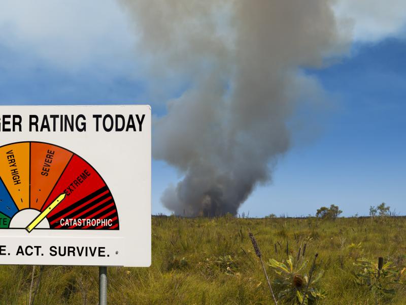 Fire danger sign with bushfire in background