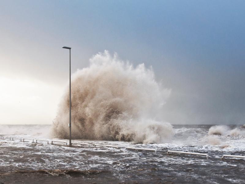 Large waves crashing on flooded road