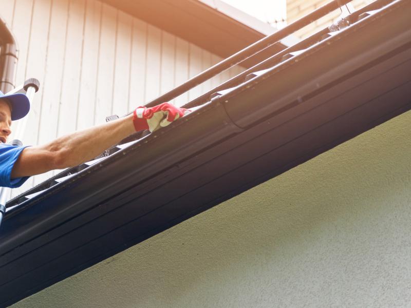 Man on ladder cleaning gutters