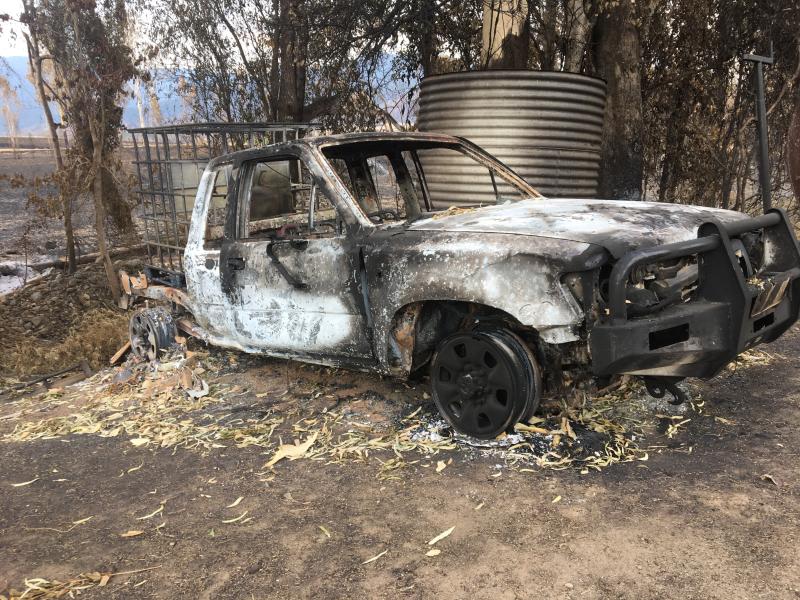 Burnt out ute next to water tank