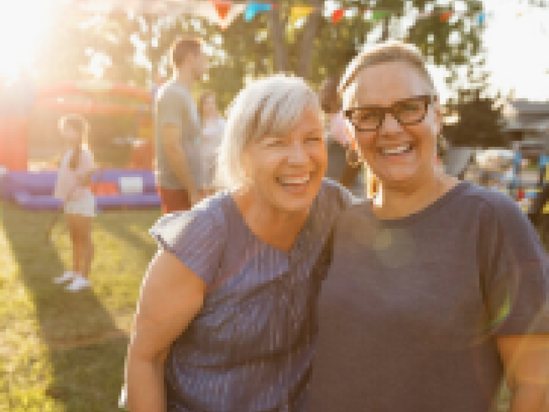 Two women talking and laughing at a community event.