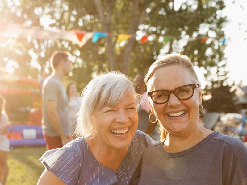 Two women talking and laughing at a local community barbecue. 