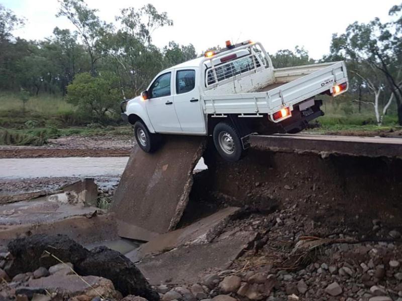 White Ute perched on edge or floodwater damaged road