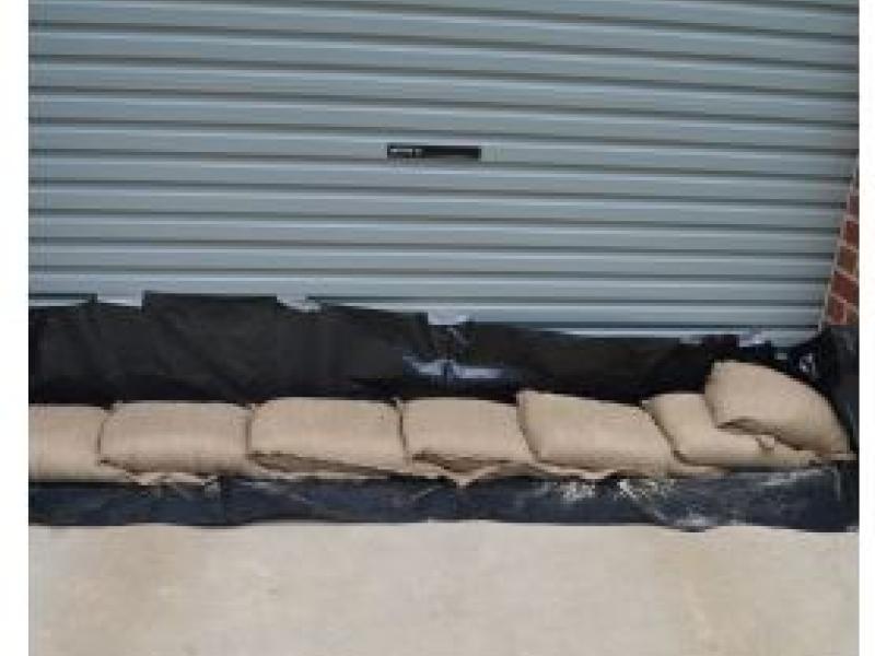 Sanbags lying on black plastic sheet in a line